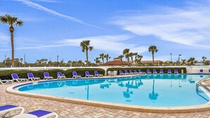 A swimming pool with blue water, surrounded by lounge chairs and palm trees. - Ocean View Unit 3305 - Ocean & Racquet Resort [20% DISCOUNT ON 7+ NIGHT STAYS] (St. Augustine Beach)