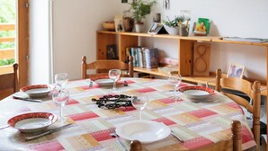Une table à manger, avec des assiettes, des verres et des couverts, entourée de chaises.