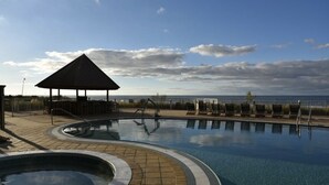 A swimming pool with a gazebo and lounge chairs, surrounded by a fence and a view of the sea. - ☀️ ☀️ BEACH FRONT - BOOKING SPRING & SUMMER - BEACH CHAIR SERVICE INCLD☀️ ☀️ (Panama City Beach)