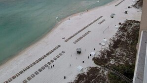 A beach with a row of white tents and a pier extending into the water. - ☀️ ☀️ BEACH FRONT - BOOKING SPRING & SUMMER - BEACH CHAIR SERVICE INCLD☀️ ☀️ (Panama City Beach)