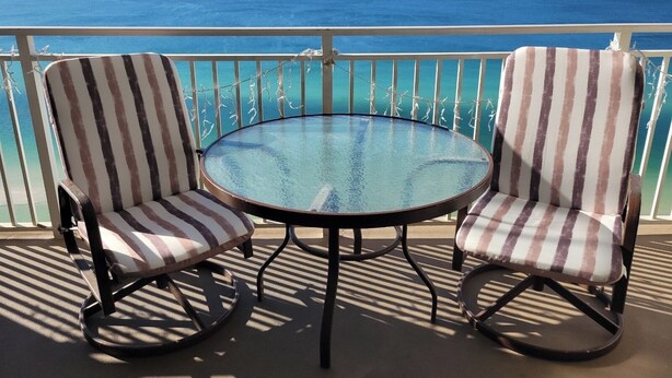 Two striped chairs and a round table on a balcony with a view of the ocean. - ☀️ ☀️ BEACH FRONT - BOOKING SPRING & SUMMER - BEACH CHAIR SERVICE INCLD☀️ ☀️ (Panama City Beach)