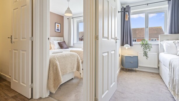 Een slaapkamer met een bed, nachtkastje, lamp en uitzicht.