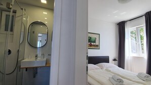 A hotel room with a shower, a sink, a bed with white linens, a bedside table, a lamp, and a window with curtains. - Beach house Villa Antares middle floor apt.A2 (Pisak)
