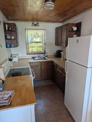 A kitchen with wooden cabinets, a sink, a stove, and a refrigerator.