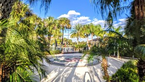 A paved plaza with palm trees, a circular design, and a building in the background. - Lake View 3BR Condo ...Near Disney and Shopping (Kissimmee)