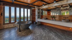 A bathroom with a large freestanding bathtub, a wooden vanity, and a large mirror. - Simply Spectacular Luxury Ocean View Villa!  (Uvita)