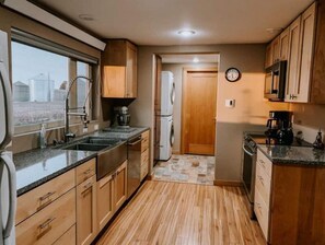 Kitchen features an oven, microwave, and stainless steel sink under a window with an outside view.