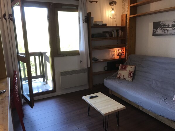 A cozy living room with a sofa, a small table, and a bookshelf.