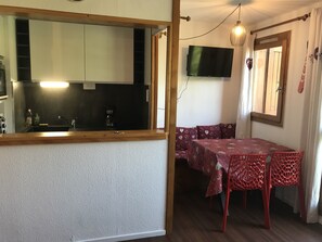A compact kitchen with a sink, coffee maker, and cabinets. A dining area with a table and chairs is visible.