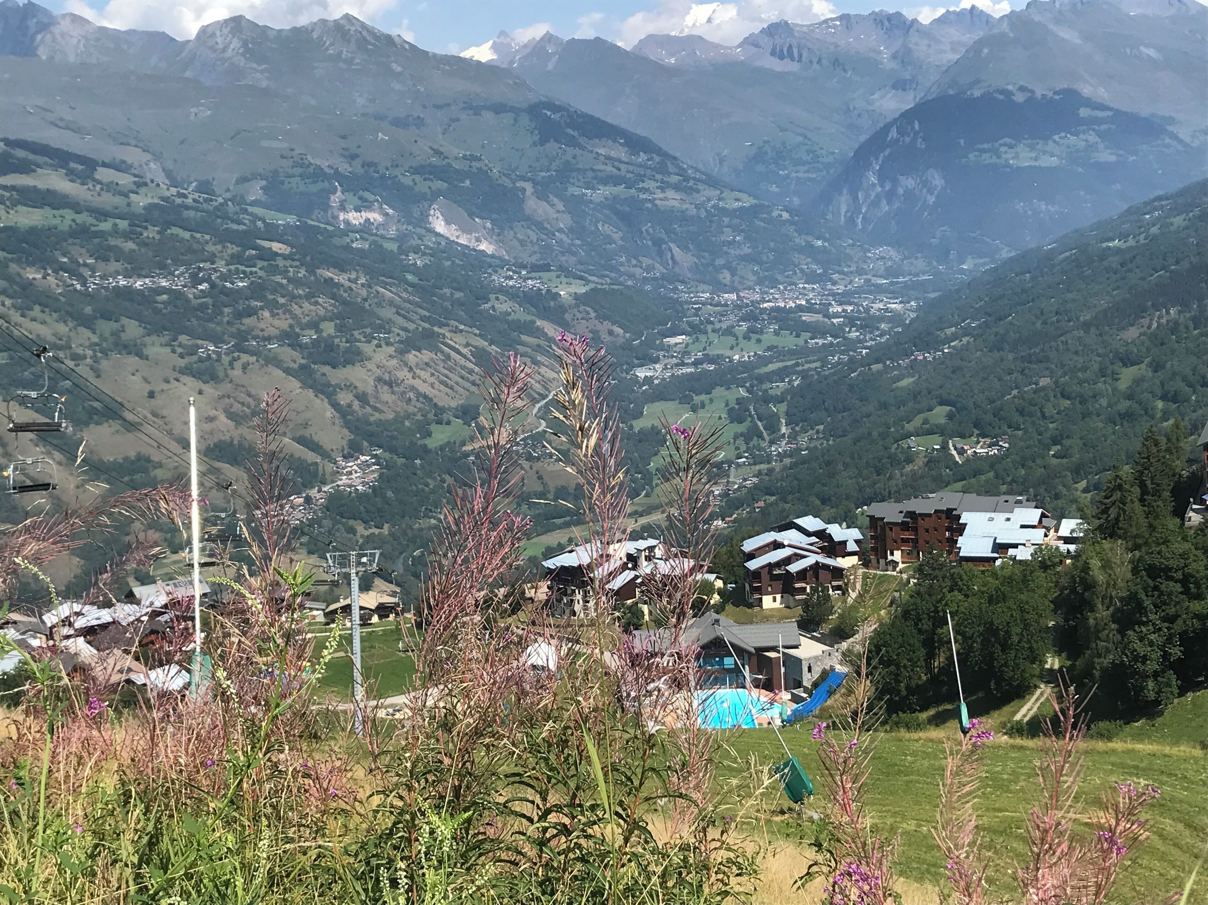 A mountainous landscape with a village, houses with sloped roofs, and a ski lift.