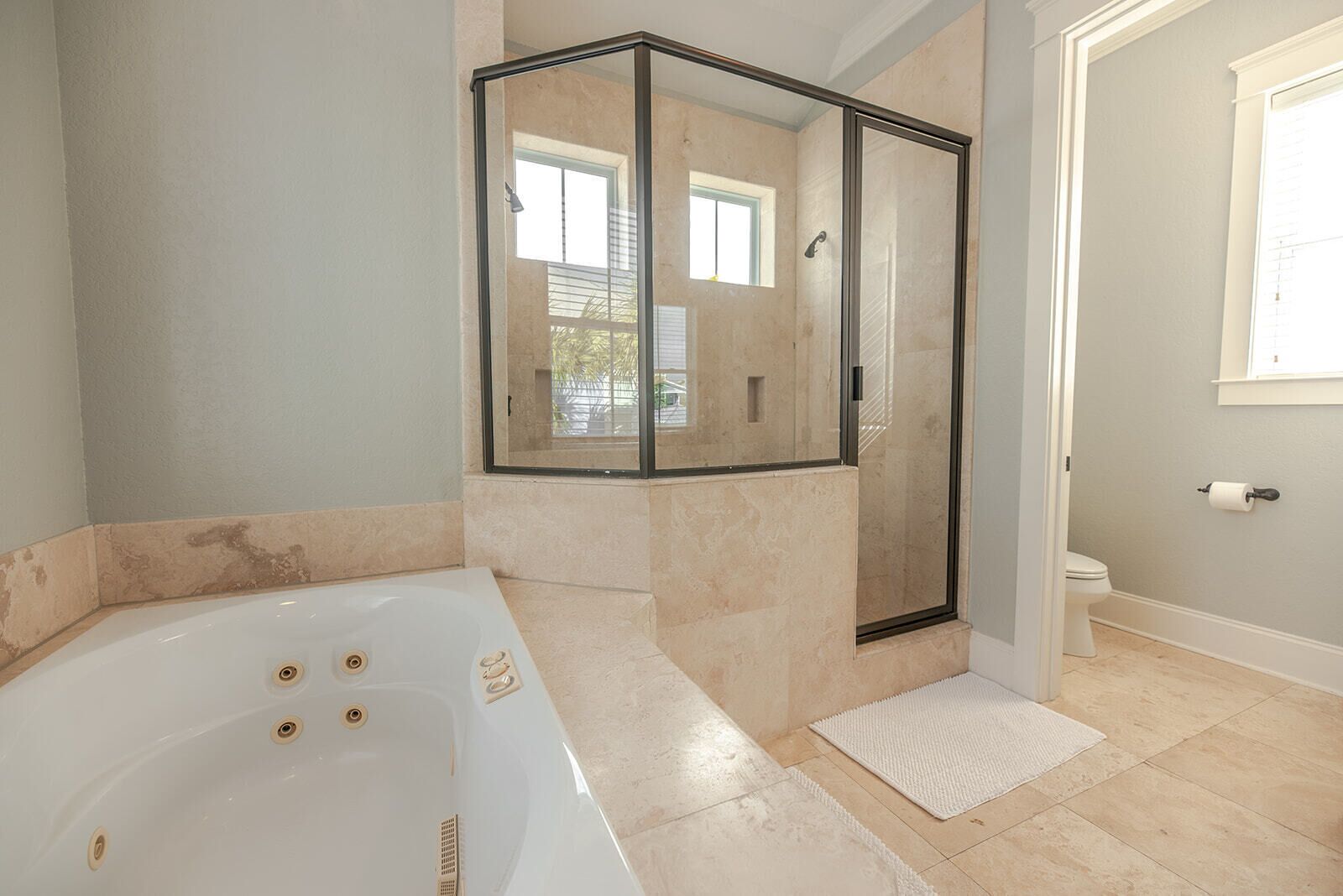 Et badeværelse med badekar, brusebad med glasvægge og toilet.