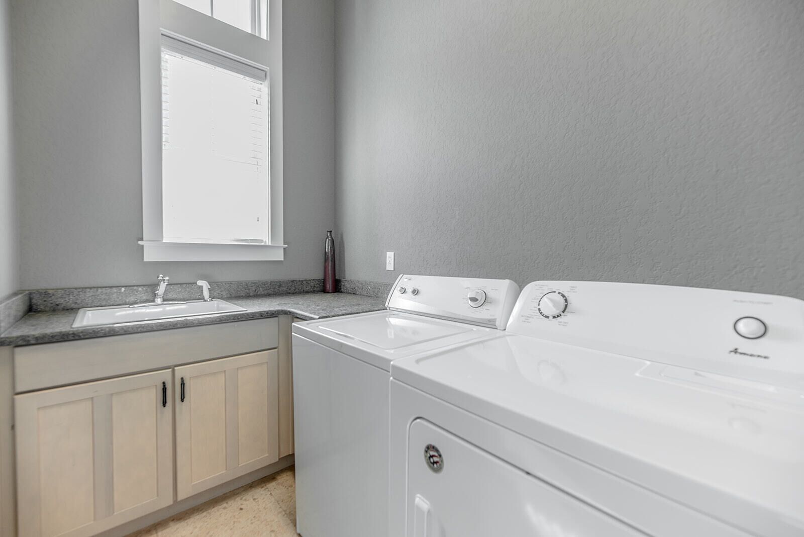 A laundry room with a washing machine, dryer, and sink.
