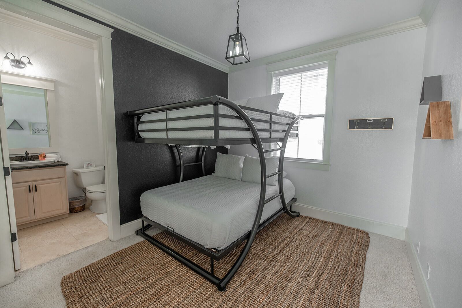 A bunk bed room with a window, a sink, and a mirror.