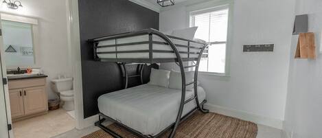 A bunk bed room with a window, a sink, and a mirror.