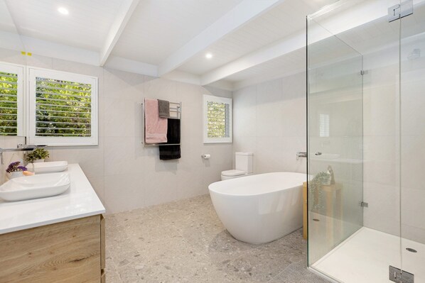Une salle de bain moderne avec une baignoire sur pieds, une douche à parois de verre et un meuble-lavabo avec un évier et un miroir.