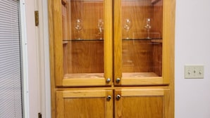 A wooden cabinet with glass doors containing wine glasses. - Chateau 11, spacious townhouse in Tickfaw, LA (Tickfaw)