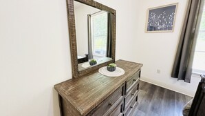A bathroom with a wooden vanity, a large mirror, and a framed picture on the wall. - Chateau 11, spacious townhouse in Tickfaw, LA (Tickfaw)