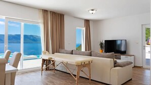 Ein modernes Wohnzimmer mit Sofa, Fernseher und Meerblick.