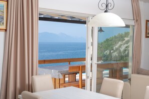 Una stanza con vista sul mare e sulle montagne, un tavolo di legno e una panca.