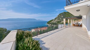 Eine Terrasse mit Meerblick, ein Balkon mit Geländer und Gartenmöbel.