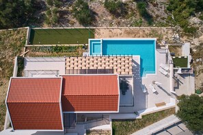 Vista aerea di un edificio moderno con piscina, area relax all'aperto e prato curato.