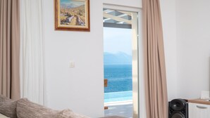 Ein Zimmer mit einem Bett, einem Gemälde, einer Musikanlage und Blick auf das Meer.