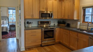 A modern kitchen with wooden cabinets, stainless steel appliances, and a large window providing natural light. - Downtown Loft on Lupfer (Whitefish)
