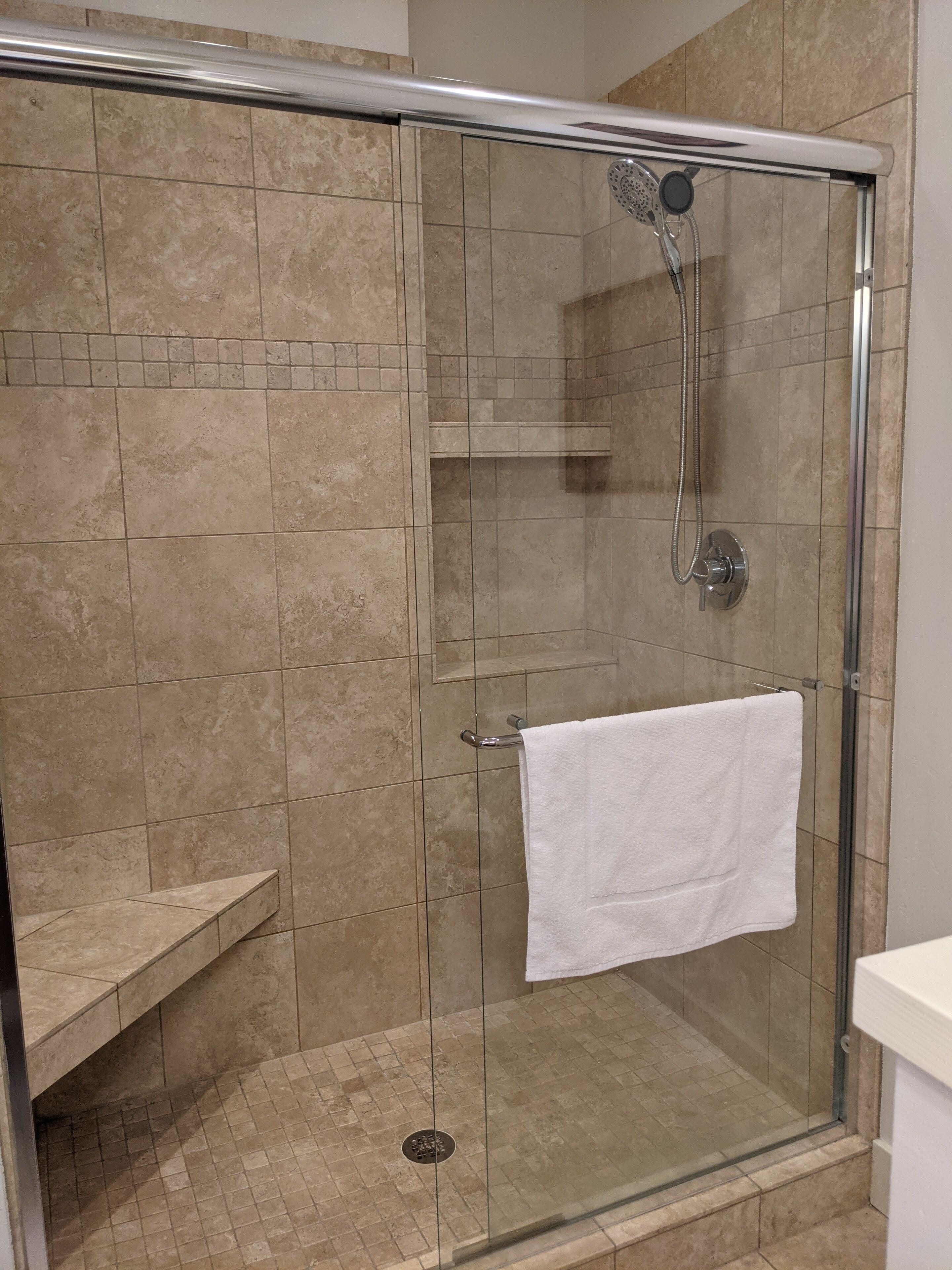 large shower with a seat/ledge and built in storage shelves for your necessities