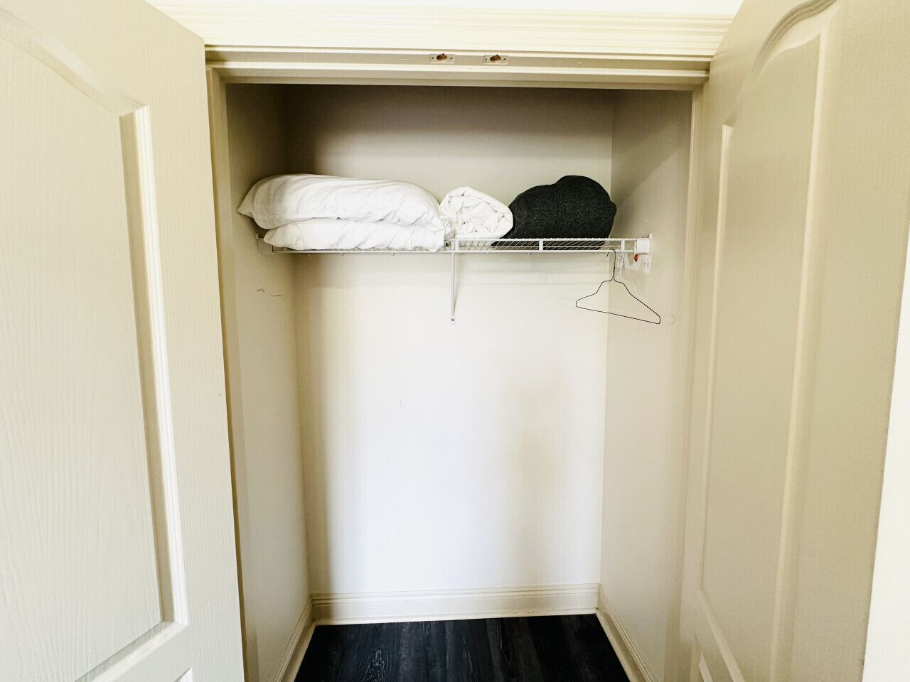 A small, white closet with a hanging rod and a shelf.