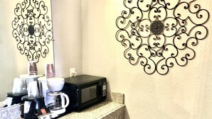 Un plan de travail de cuisine avec une machine à café, un four à micro-ondes et un évier.