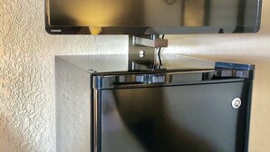 Un petit réfrigérateur noir, doté d’un écran numérique sur le dessus, fixé à un mur à texture.