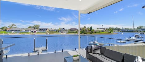 A balcony with a view of a marina, outdoor furniture, and a clear sky.