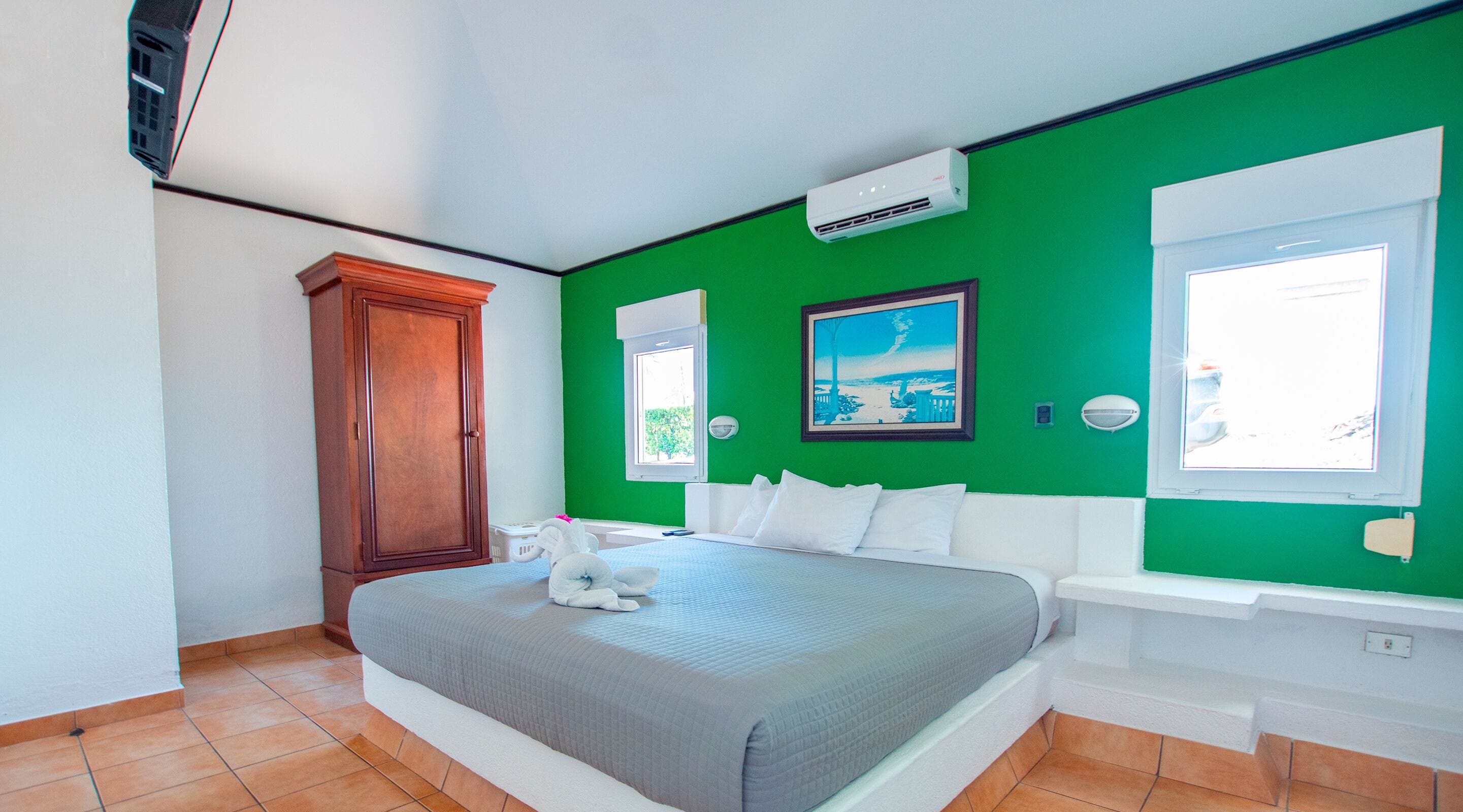 A bedroom with a bed, a wardrobe, a painting, and a window.