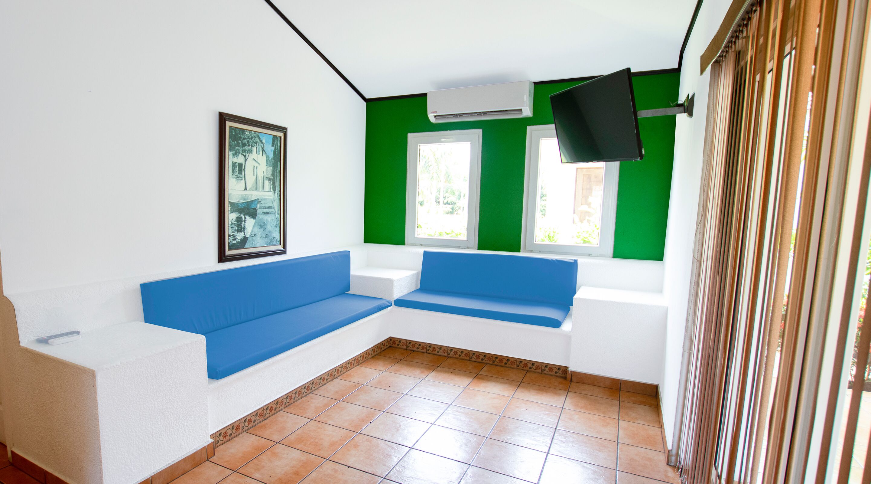 Une pièce avec un canapé bleu, un tableau encadré au mur et une fenêtre donnant sur un paysage verdoyant.