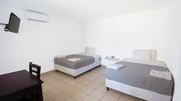 Une petite chambre propre, avec deux lits simples, un bureau et une chaise.