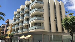 Un immeuble résidentiel à plusieurs étages, doté de balcons, donnant sur une rue et devant lequel est garavané un fourgon.