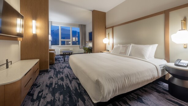 Ein Hotelzimmer mit einem großen Bett, einem Schreibtisch, einem Stuhl und einem Fenster mit Bergblick.
