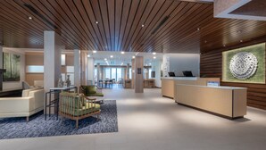 Eine moderne Lobby mit Holzboden, einer Rezeption und einer Sitzecke mit einem Spielbereich für Kleinkinder.