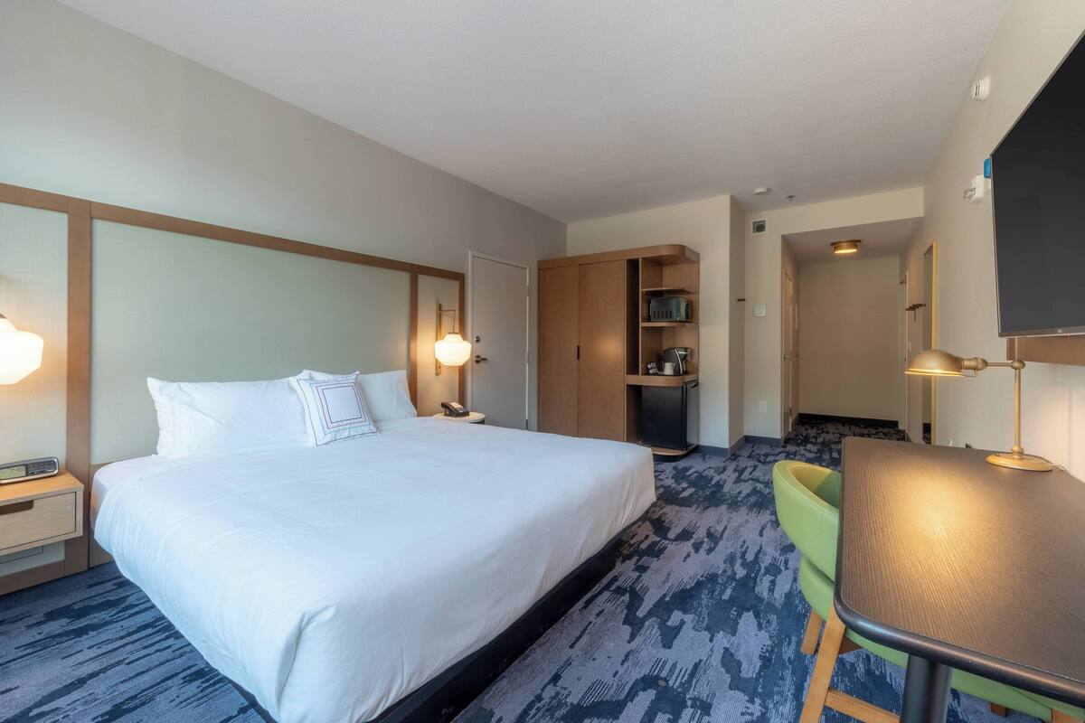 A hotel room with a large bed, bedside tables, a desk, and a chair.