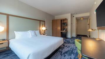 A hotel room with a large bed, bedside tables, a desk, and a chair.