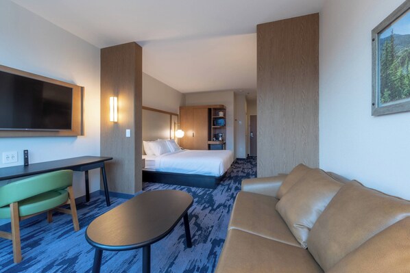 Una habitación de hotel con cama, escritorio con silla, sofá y televisor.