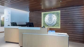 Un taulell de recepció amb un mur de panells de fusta i una gran obra d'art abstracta a la part superior.