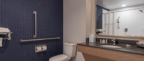 Un baño moderno con una pared azul con textura, un inodoro blanco, un tocador de madera con lavabo y un espejo grande.