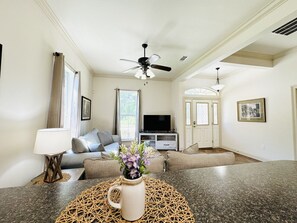 A living room with a sofa, TV, and a ceiling fan. - Villa 2, spacious townhouse in Tickfaw, LA (Tickfaw)