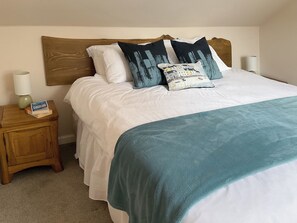 A neatly made bed with a wooden headboard, white bedding, and a teal throw blanket. There are two bedside tables with lamps and a small book on one. - 2 bedroom accommodation in Edzell, near Brechin (Edzell, near Brechin)