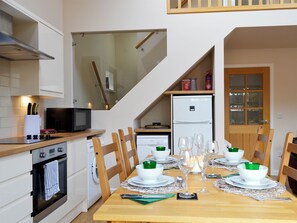 A compact kitchen with modern appliances, a dining area with a set table, and a staircase leading to an upper level. - 2 bedroom accommodation in Edzell, near Brechin (Edzell, near Brechin)