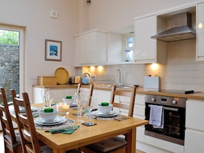 A modern kitchen with white cabinets, a stainless steel oven, and a dining area set for a meal.