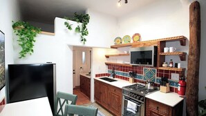 Une cuisine compacte équipée d’une cuisinière, d’un évier et de meubles de rangement en bois. On y trouve également un coin repas avec une table et des chaises.