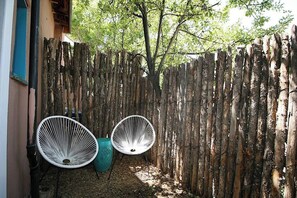 A wooden fence, two white chairs, and a tree in a garden area. - Closson Getaway- Courtyard | Railyard and Plaza (Santa Fe)