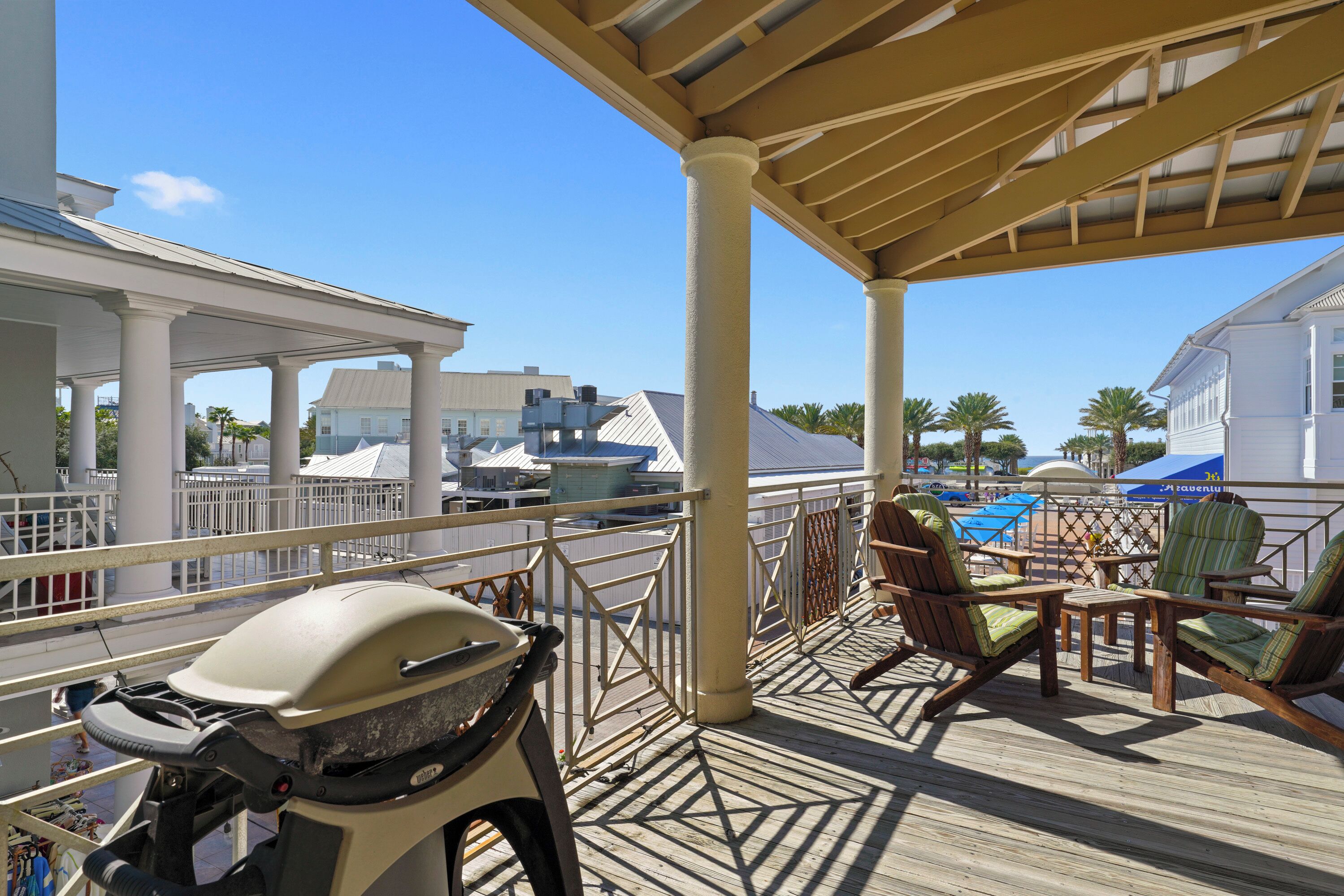 A covered outdoor deck with a grill, chairs, and a view of the marina.